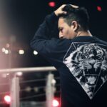 Jak pokochać życie? Refleksja. Na zdjęciu chłopak trzyma się za głowę i myśli, w nocy stoi na moście.