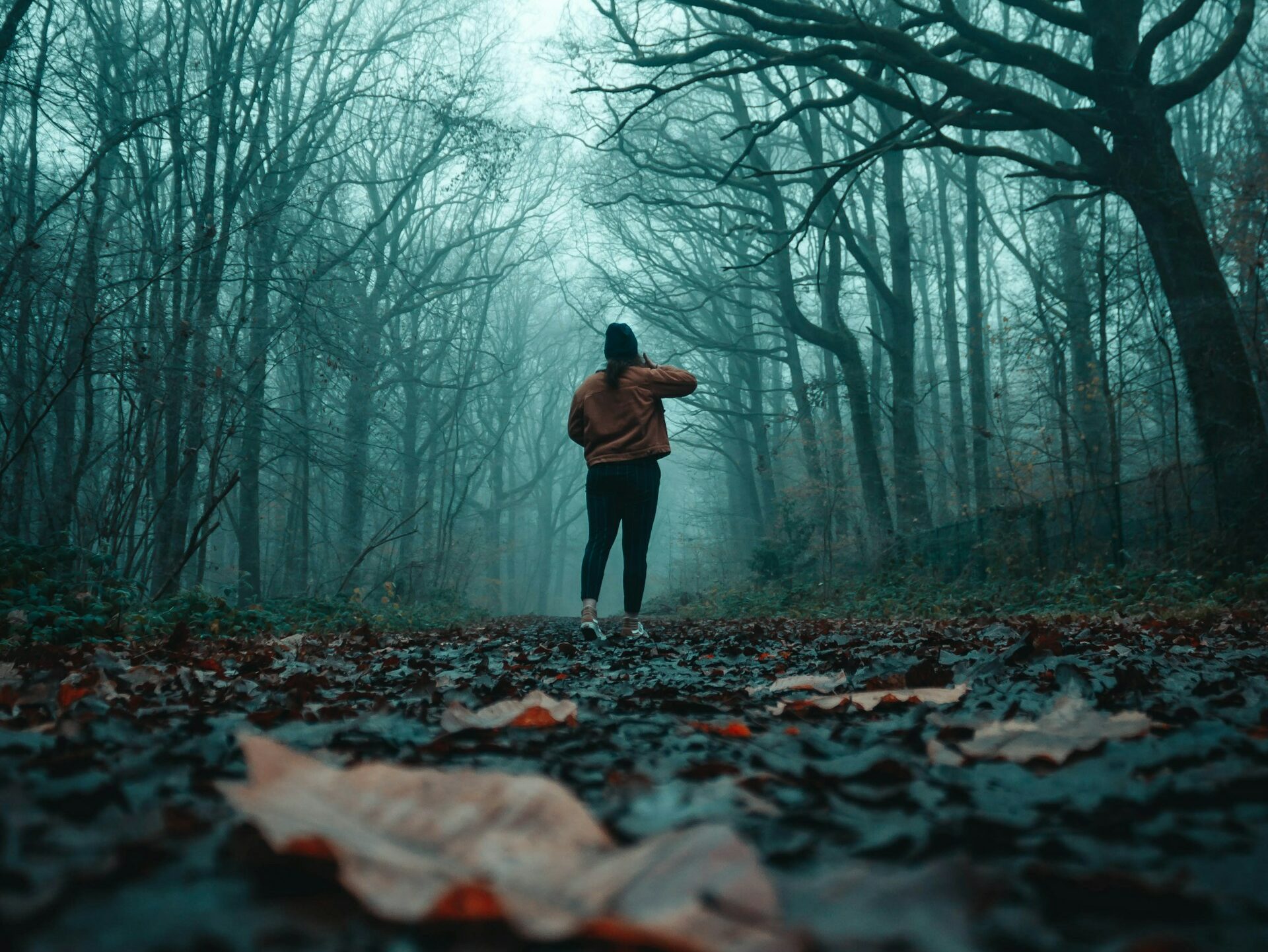 Kobieta stoi w lesie na drodze, wokół mgła