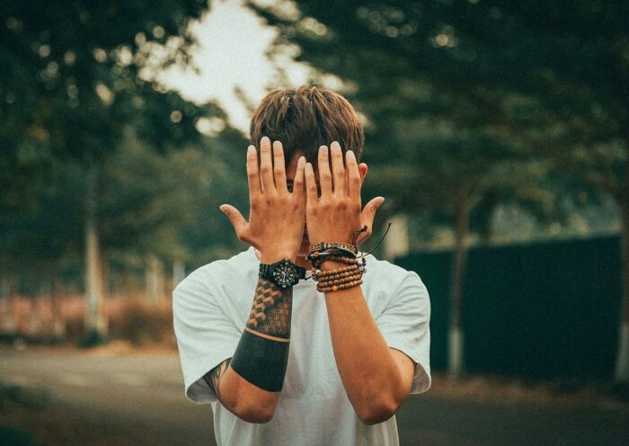 jak często chodzić do spowiedzi. Młody chłopak trzyma dłonie na twarzy.